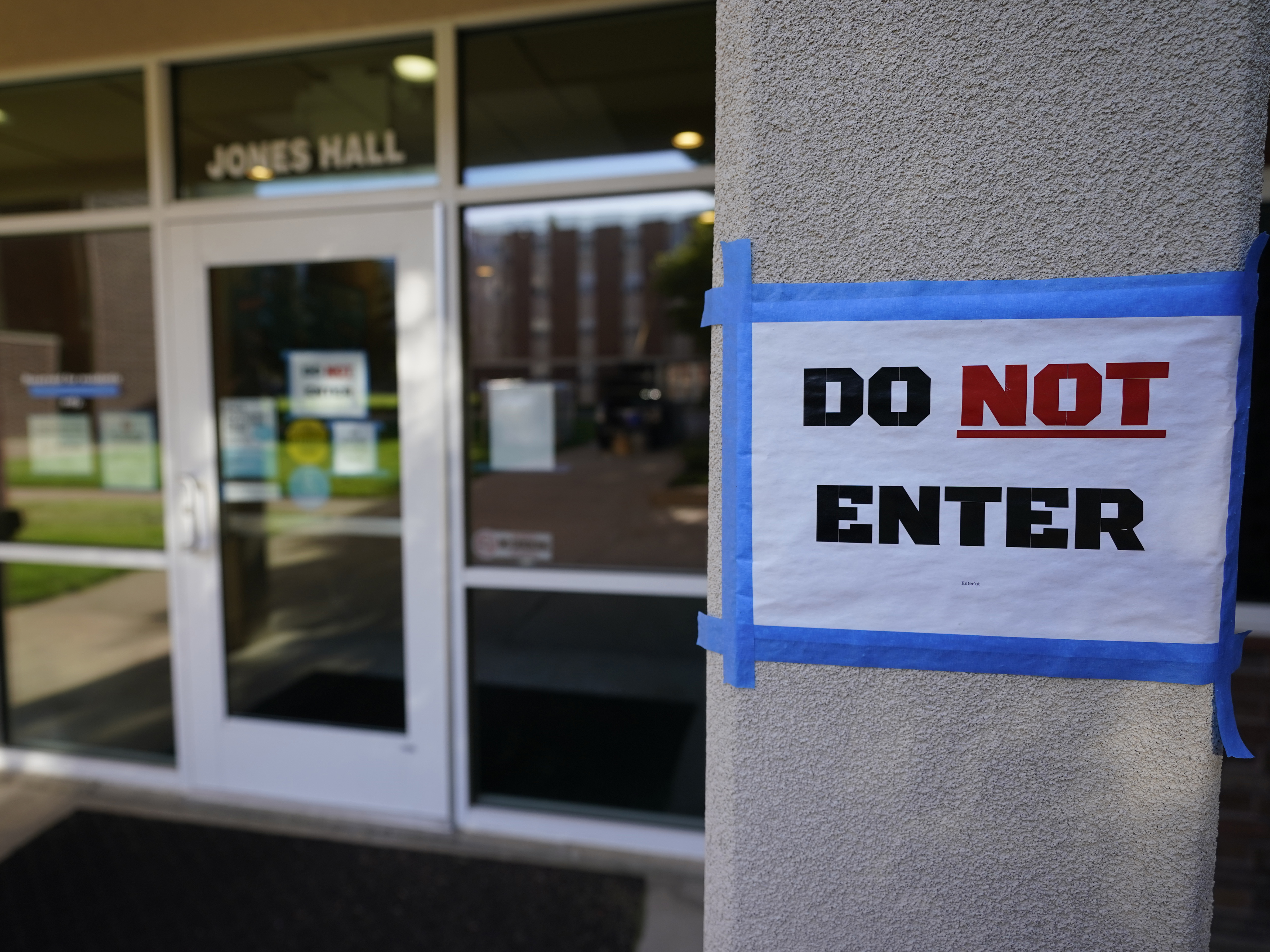 caption: The doorway to Jones Hall is shown at Utah State University in September, where about 300 students were being quarantined to their rooms as a precaution.
