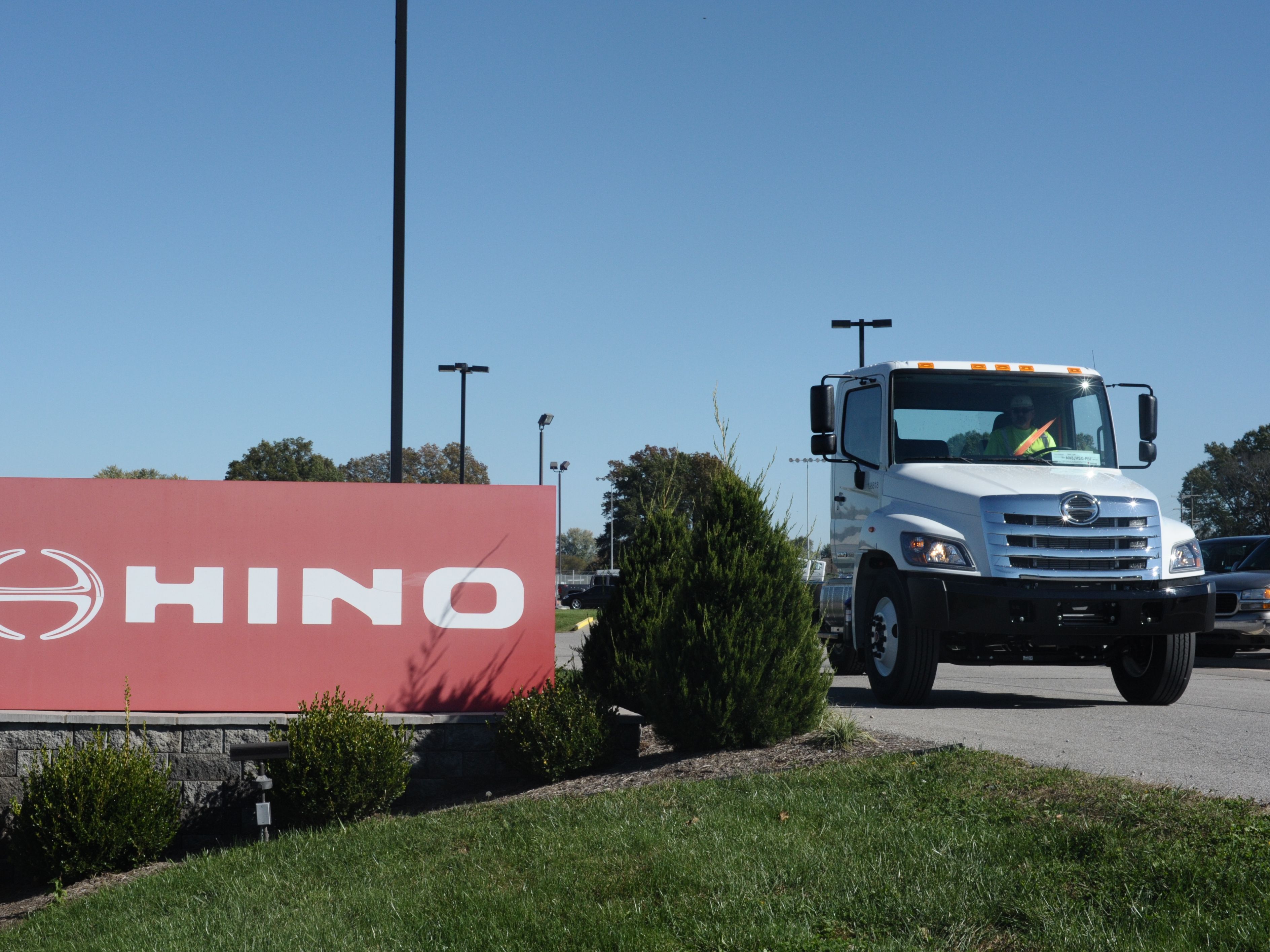 caption: A truck passes a Hino sign in Williamstown, W.V., in 2017. The truck manufacturer, a Toyota subsidiary, has agreed to plea guilty to federal conspiracy charges and pay a total of $1.6 billion to settle civil claims after regulators discovered it was submitted fraudulent data to evade emissions standards.