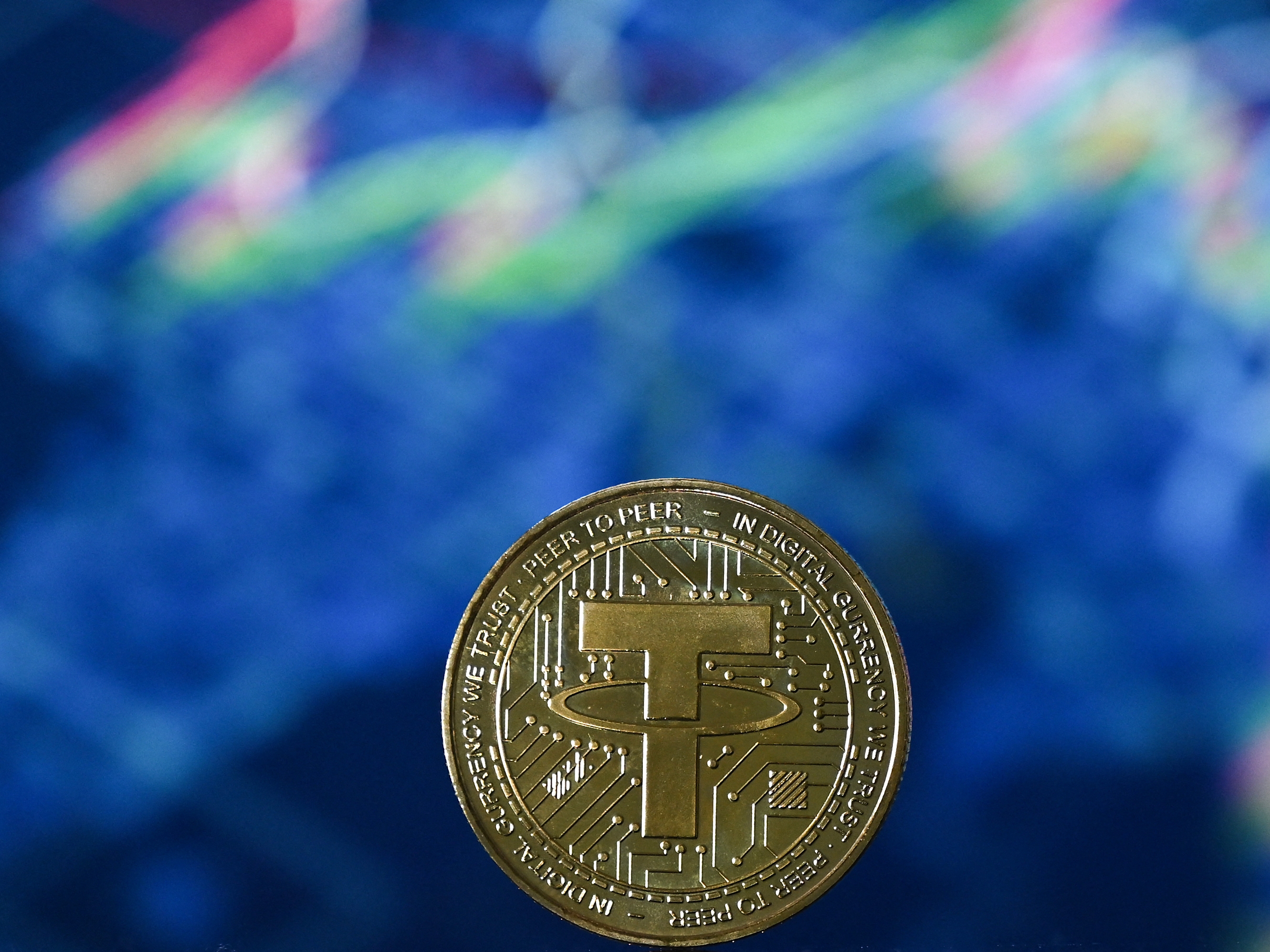 caption: A picture taken in London shows a gold-plated souvenir stablecoin issued by Tether.