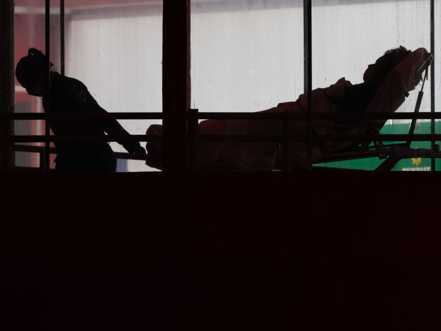 caption: An EMT wearing protective equipment moves a patient into Elmhurst Hospital Center in the Queens borough of New York. Preliminary data suggest COVID-19 is having a disproportionate impact on communities of color.
