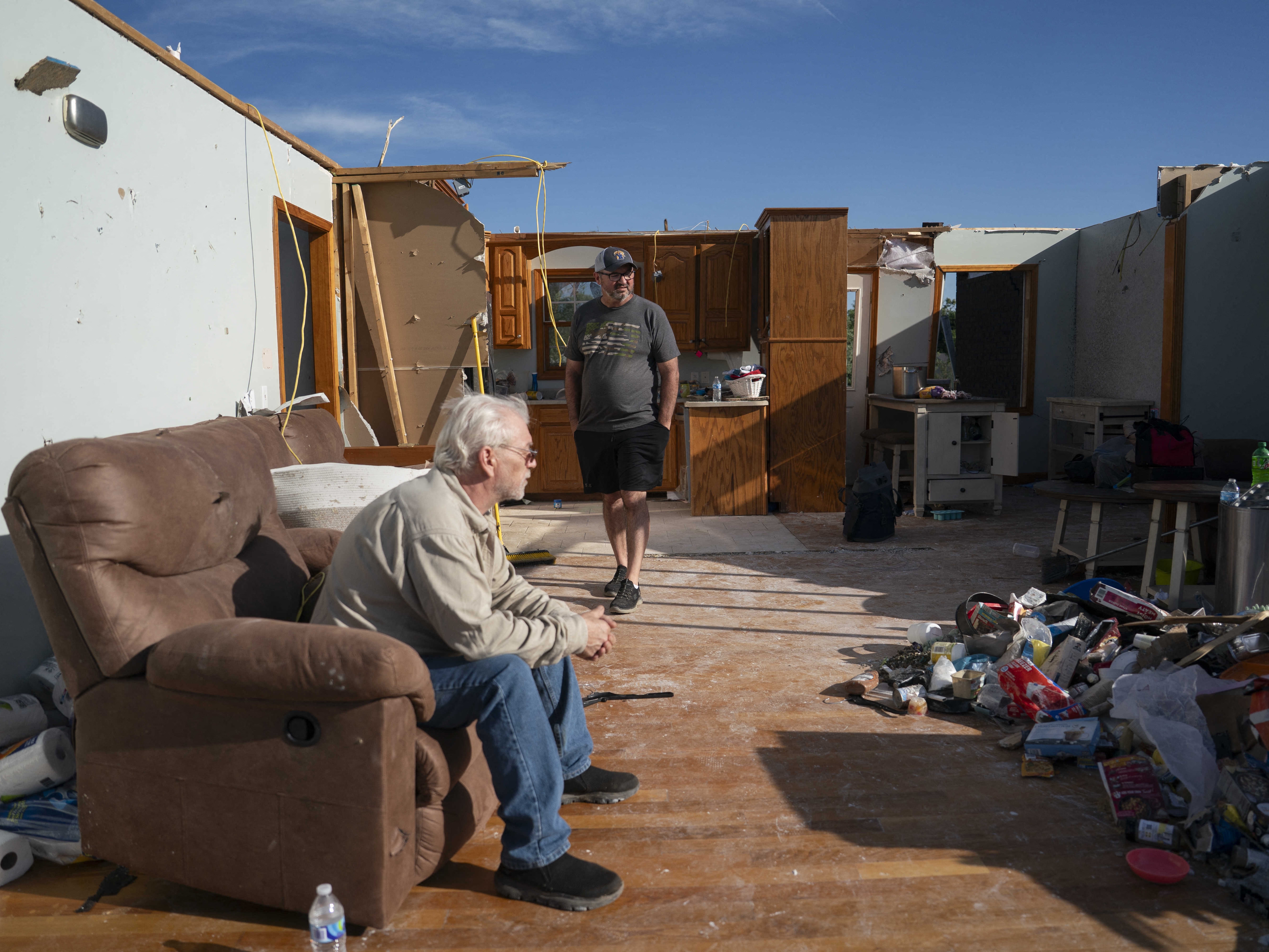 caption: People in the remnants of a home in London, Kentucky after it was hit by a tornado in May 2025. Home insurance costs are expected to increase this year in states that have suffered hail and tornado damage from big convective storms.