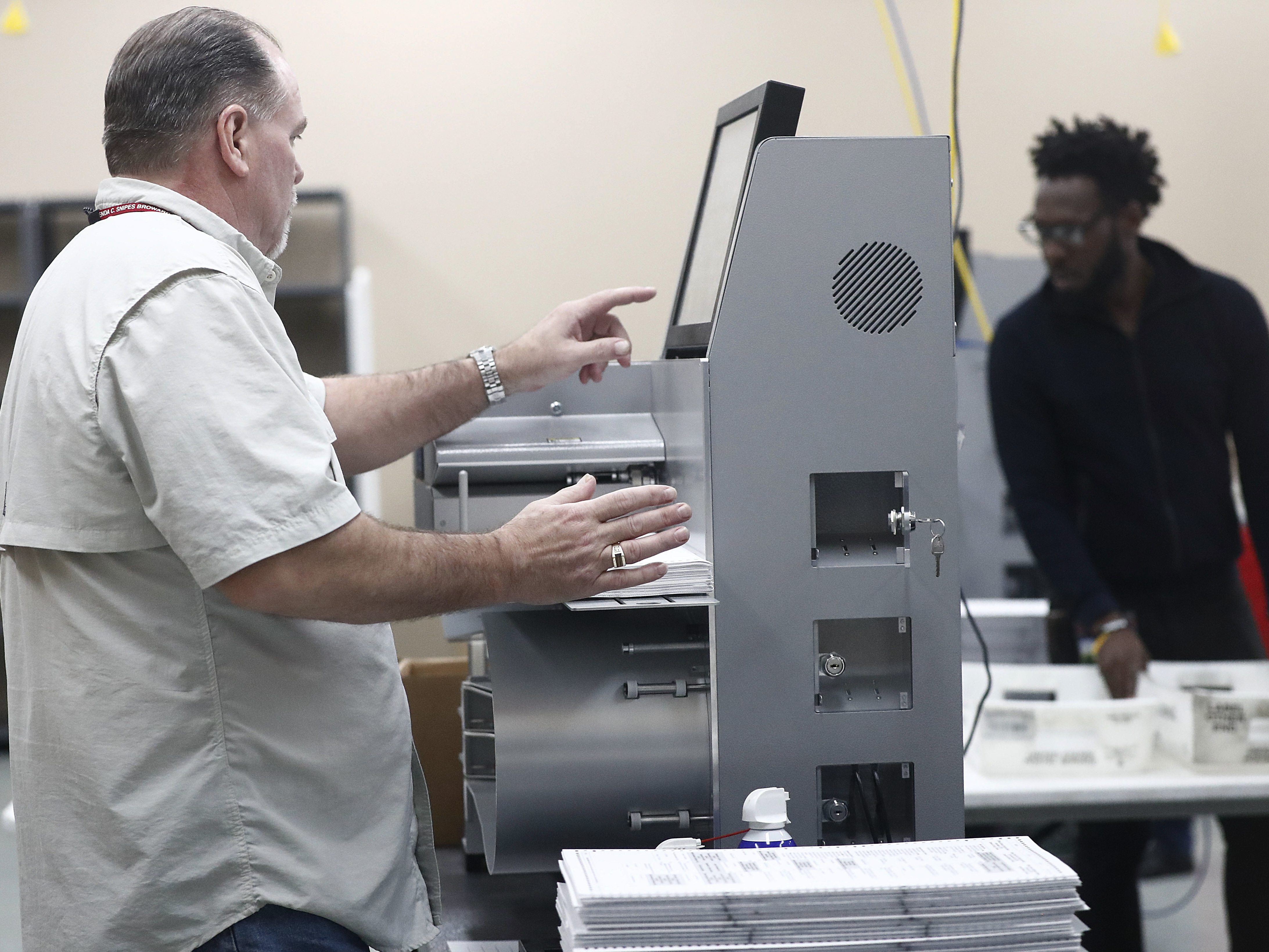 caption: Workers load ballots into machines at the Broward County Supervisor of Elections office during a recount on Sunday in Lauderhill, Fla.