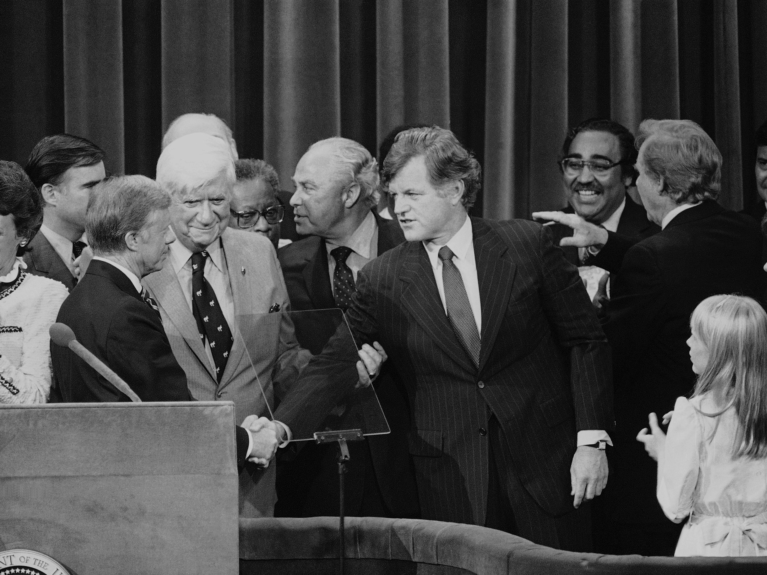 caption: Months after his challenge to the incumbent President Carter had failed, Sen. Edward Kennedy (D-Mass.) makes a belated gesture of unity in the closing moments of the 1980 National Convention.