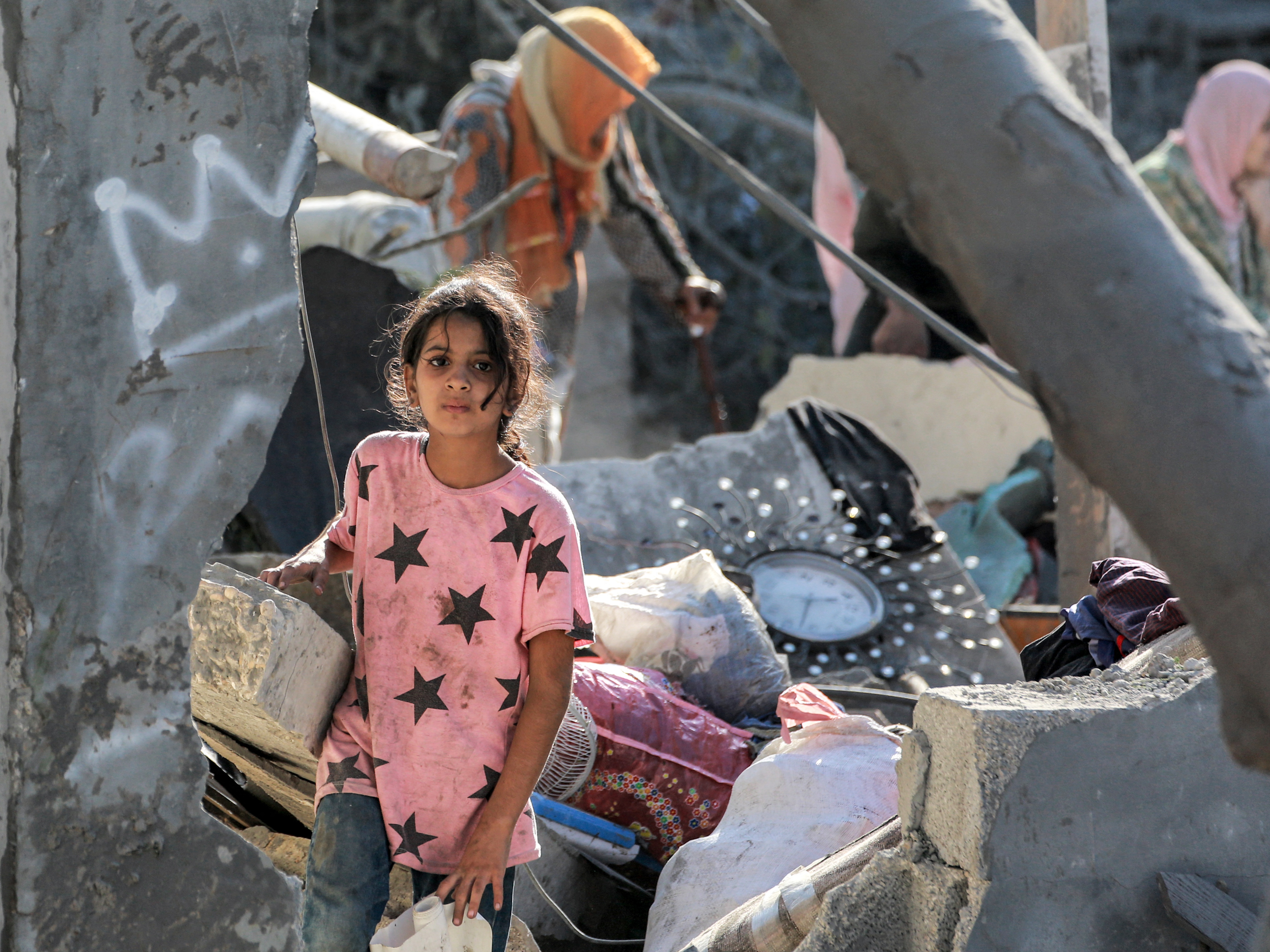 caption: A girl walks through the rubble of a collapsed building in Khan Younis, in the southern Gaza Strip, on Oct. 2, amid the war in the Palestinian territory between Israel and Hamas.