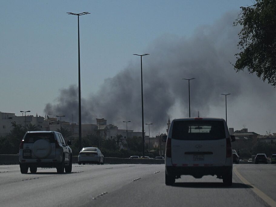 caption: Motorists drive along a street as smoke rises from a reported Iranian strike in the area where the U.S. Embassy is located in Kuwait City on Monday.