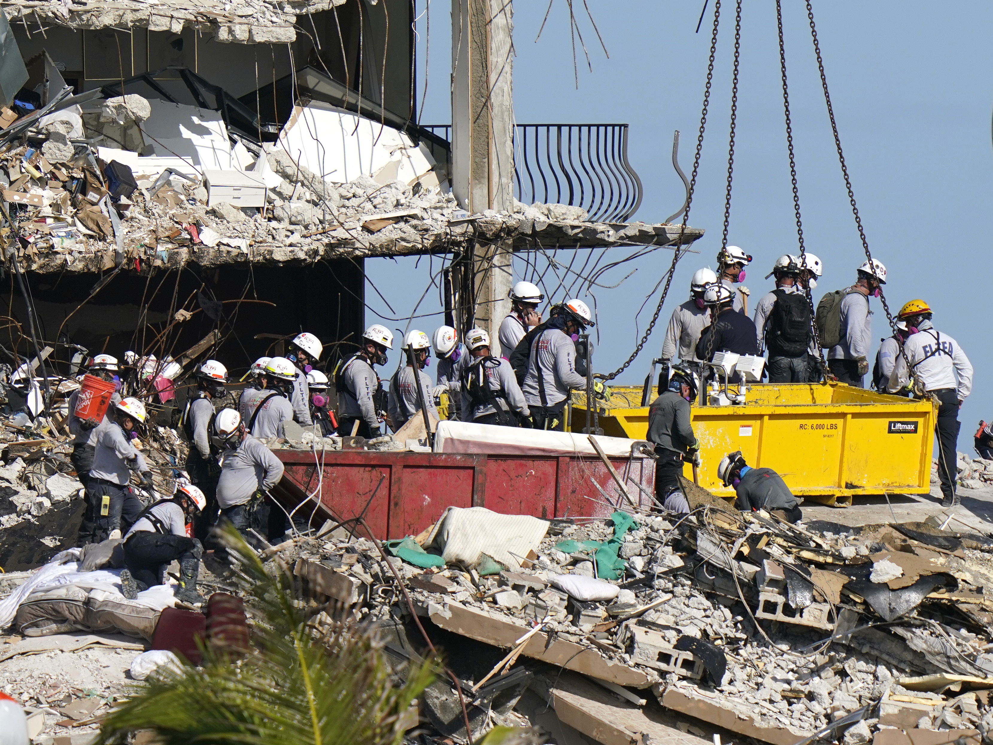 caption: Rescue workers search for survivors in the rubble at the Champlain Towers South condo building Monday in Surfside, Fla. Some 150 people remain unaccounted for after the building partially collapsed last week.