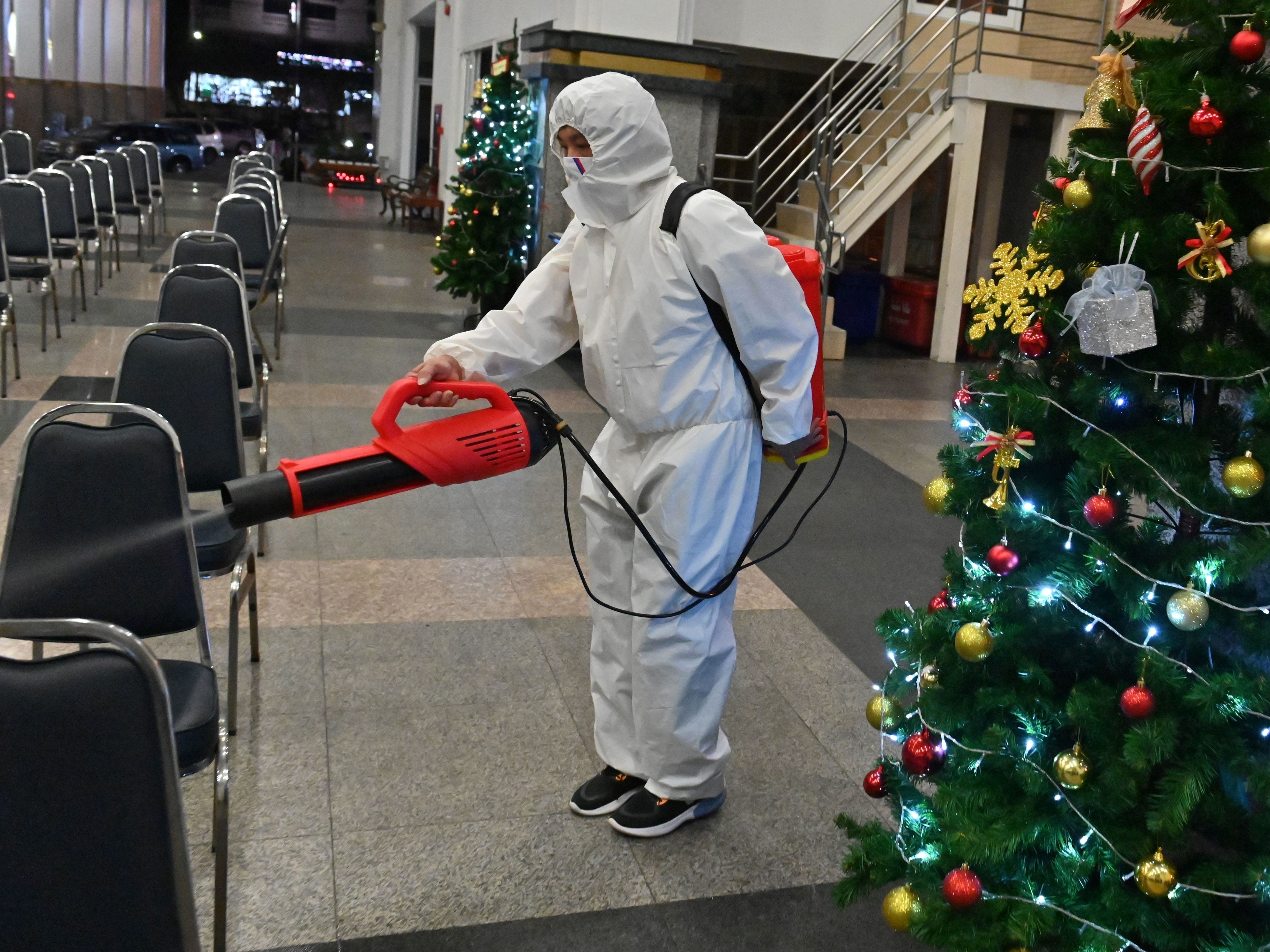 caption: A worker wearing personal protective equipment disinfects the Holy Redeemer Church in Bangkok after a Christmas Eve mass. Thailand is one of many countries now seeing a surge in cases.