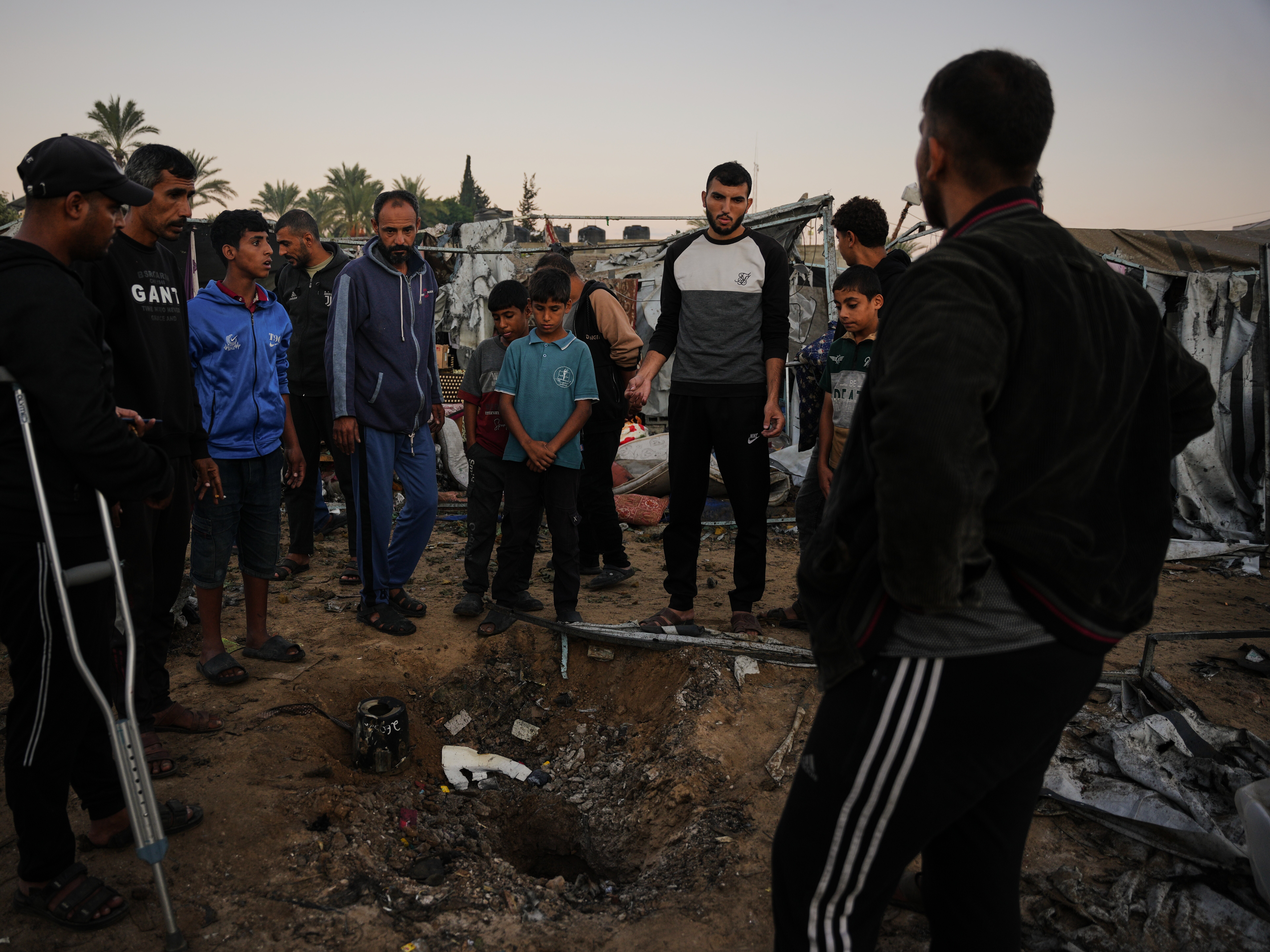 caption: Displaced Palestinians inspect the damage after an Israeli army strike on their tent camp in Deir al-Balah, Gaza Strip, Wednesday.