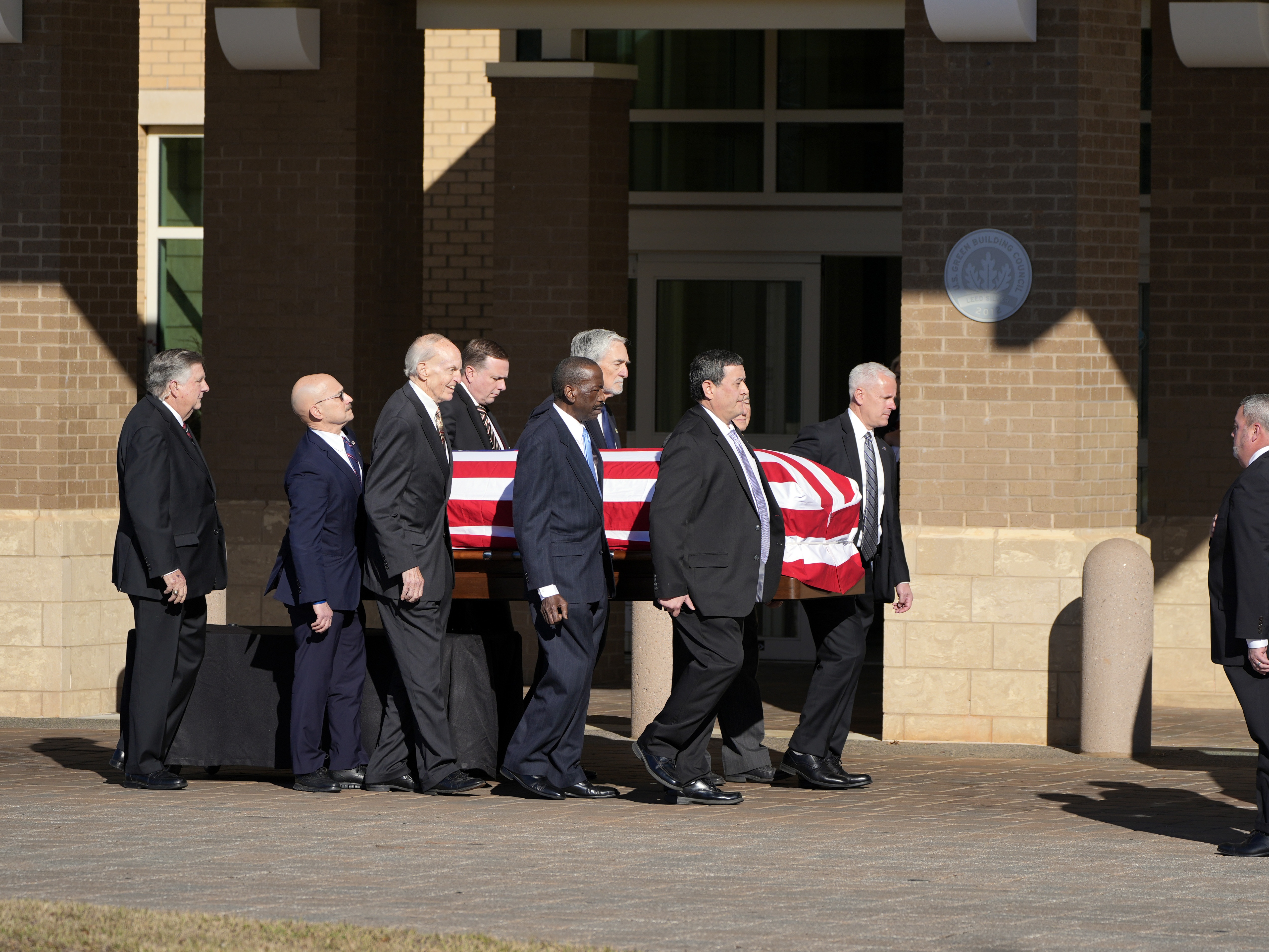 caption: Former and current U.S. Secret Service agents assigned to the Carter detail move the flag-draped casket of former President Jimmy Carter, at Phoebe Sumter Medical Center on Saturday in Americus, Ga.