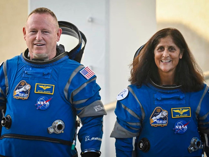 caption: NASA astronauts Butch Wilmore (L) and Suni Williams, wearing Boeing spacesuits, as they depart the operations and checkout building for the launchpad on Wednesday at the Kennedy Space Center in Florida. It's the third trip to space for both of them.