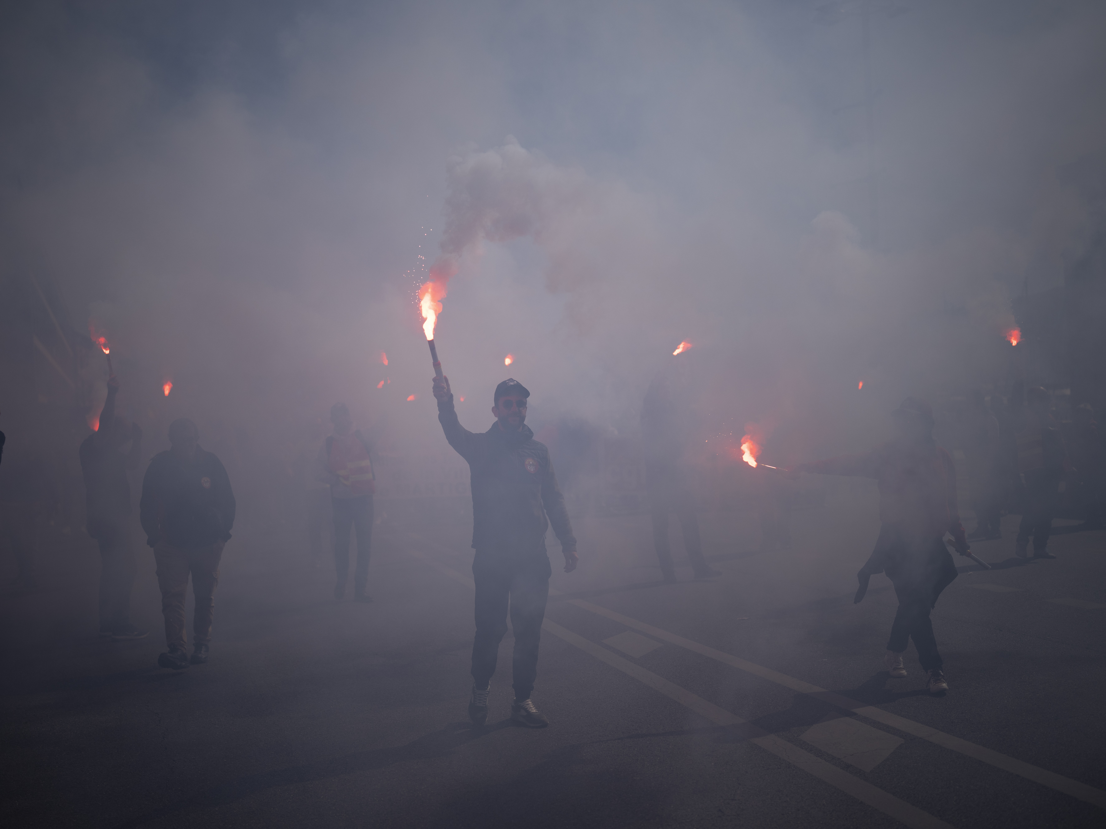 caption: Protesters march with flares during a demonstration in Marseille, southern France, on Tuesday. France's government is unfurling massively ramped-up security measures for a fresh blast of marches and strikes against unpopular pension reforms.