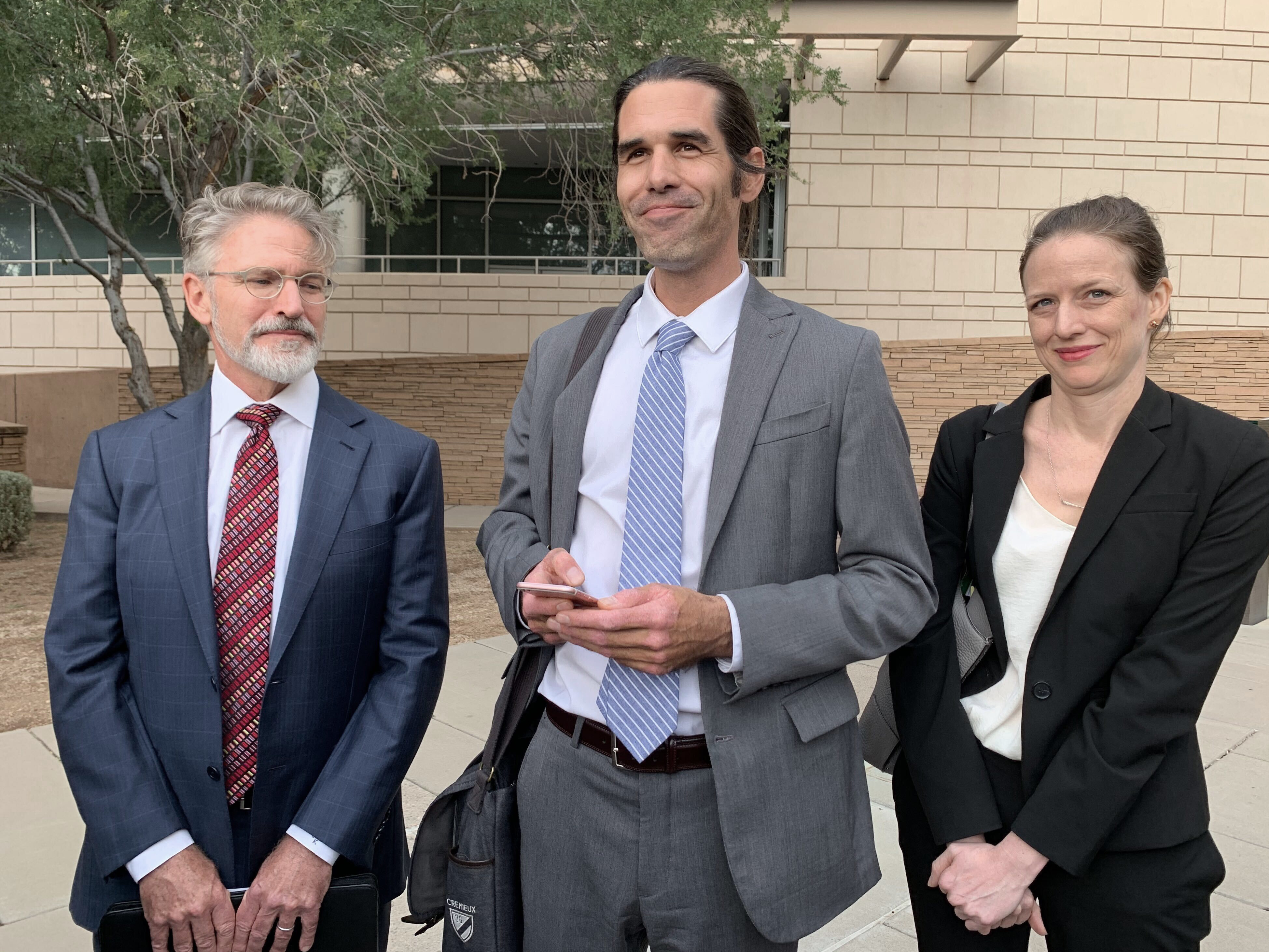 caption: Scott Warren (center) of Ajo, Ariz., celebrates with his attorneys Amy Knight and Greg Kuykendall outside court in Tucson, Ariz., on Wednesday.