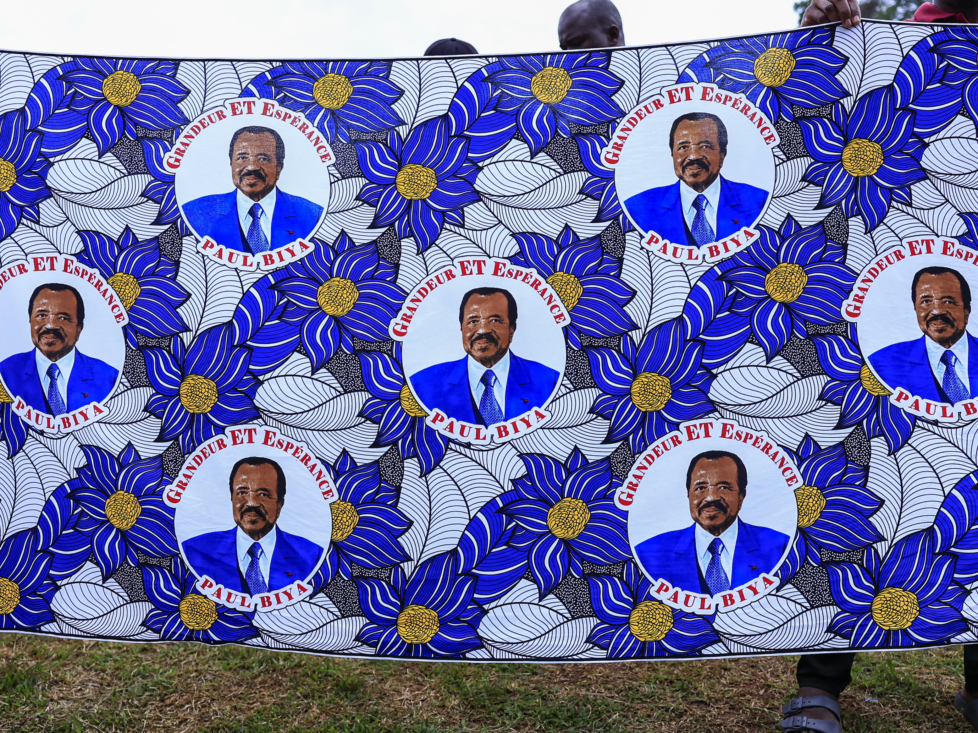 caption: Supporters of the Cameroon People's Democratic Movement (CPDM) hold the new campaign fabric bearing the image of Cameroon's President and presidential candidate Paul Biya.