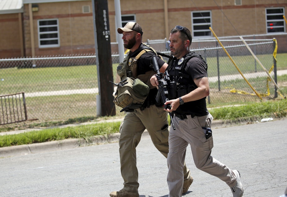 caption: Police walk near Robb Elementary School following a shooting, Tuesday, May 24, 2022, in Uvalde, Texas.