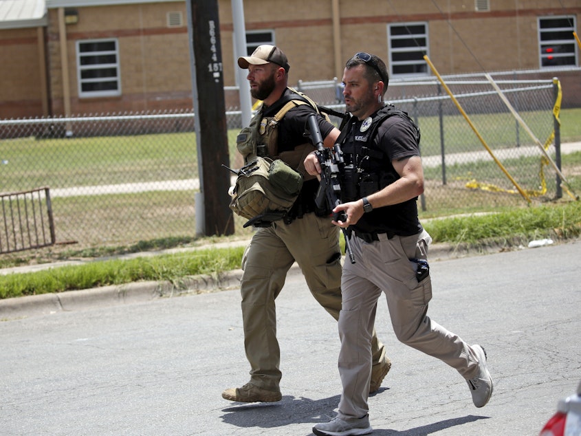 caption: Police walk near Robb Elementary School following a shooting, Tuesday, May 24, 2022, in Uvalde, Texas.