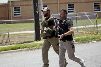 caption: Police walk near Robb Elementary School following a shooting, Tuesday, May 24, 2022, in Uvalde, Texas.