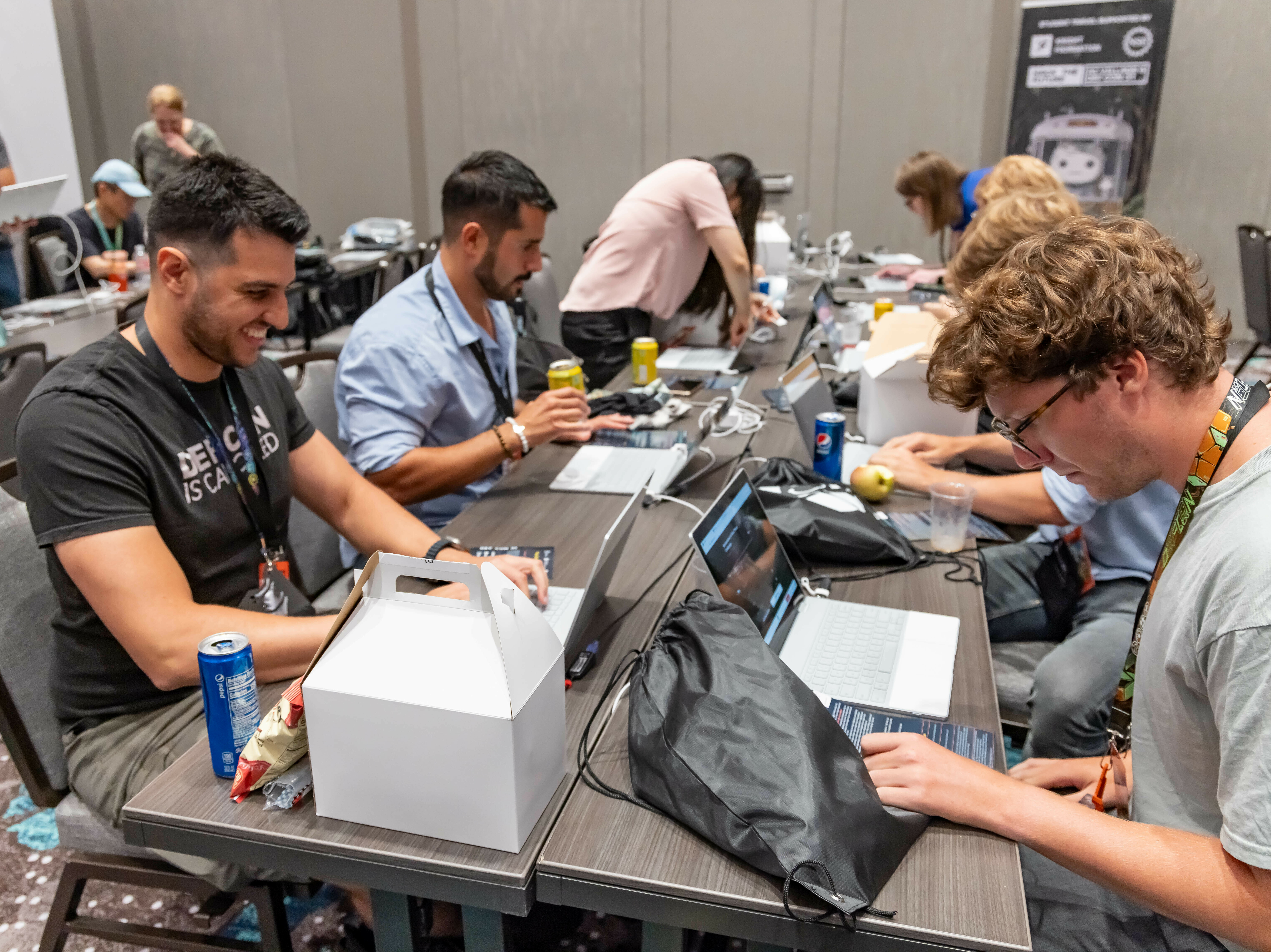 caption: Participants at the 2023 Def Con hacker convention, trying to subvert AI chatbots as part of a contest to test the systems' vulnerabilities.