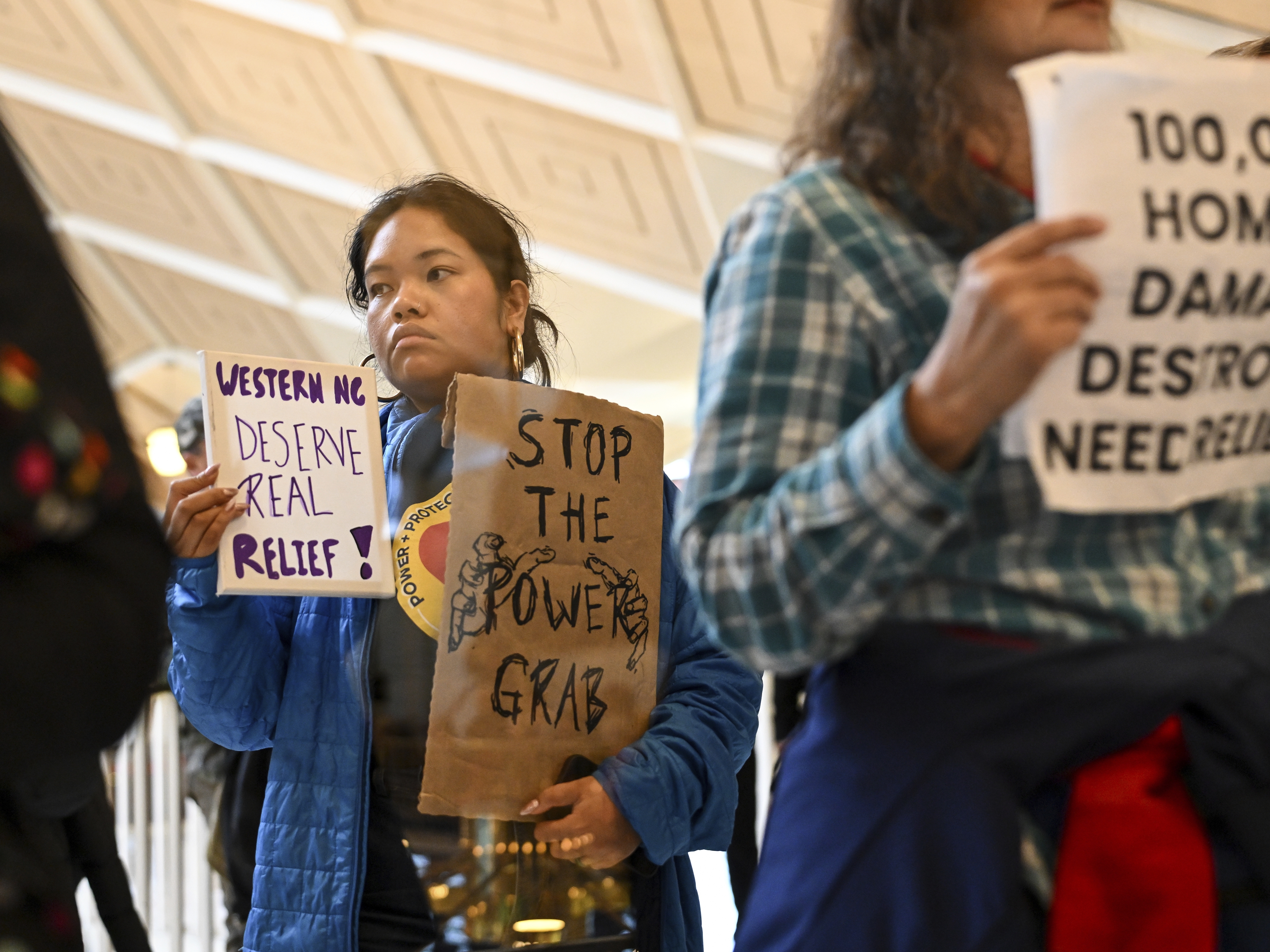 caption: A protester holds a sign as the Republican-dominated North Carolina House convened to complete the override of Gov. Cooper's veto, Dec. 11, 2024, in Raleigh, N.C.