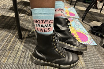caption: A trans-rights supporter wears socks reading "protect trans lives" at a meeting of Florida's medical boards on Feb. 10, 2023 in Tallahassee, Fla.
