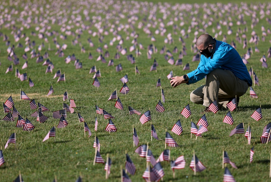 caption: Chris Duncan, whose 75 year old mother Constance died from COVID on her birthday, photographs a COVID Memorial Project installation of 20,000 American flags on the National Mall as the United States crosses the 200,000 lives lost in the COVID-19 pandemic. (White House. (Photo by Win McNamee/Getty Images)