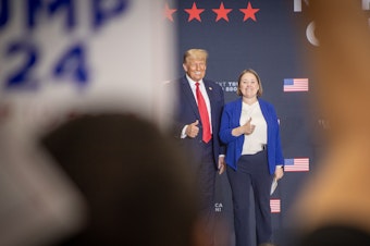 caption: Former President Donald Trump stands on stage during a rally in suburban Des Moines with Iowa Attorney General Brenna Bird after receiving her endorsement on Oct. 16.