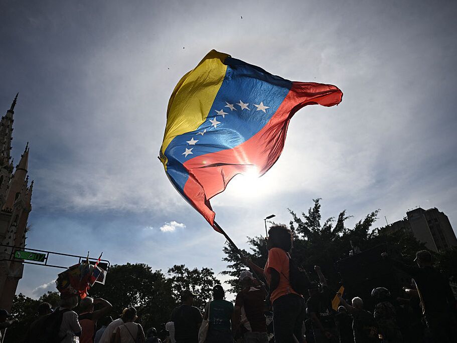 caption: A person flutters a national flag in Caracas on January 3, 2026, after US forces captured Venezuelan leader Nicolas Maduro.