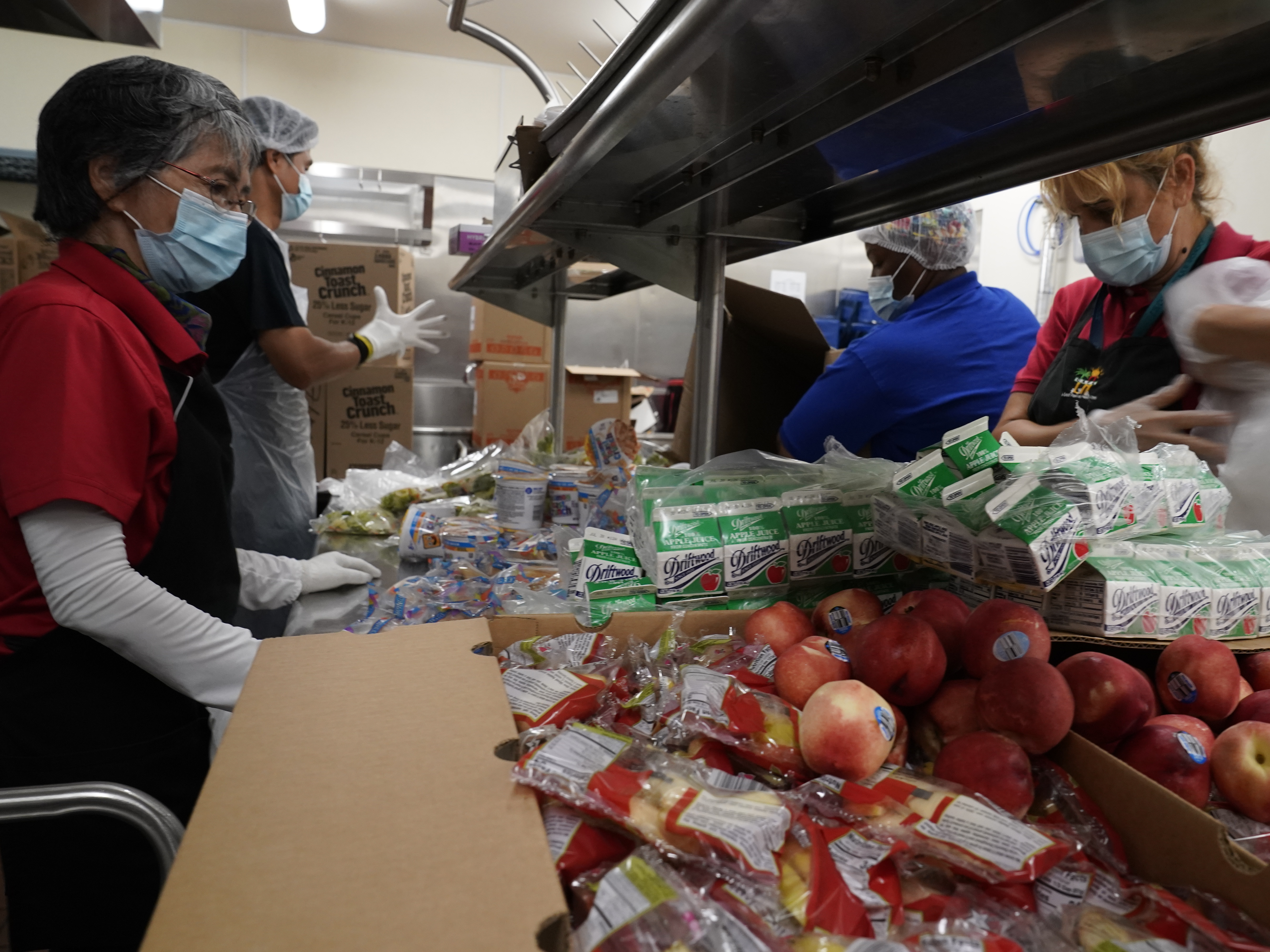 caption: Los Angeles Unified School District food service workers  pre-package hundreds of free school lunches in plastic bags.