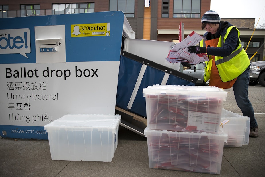 caption: FILE: King County Elections employee Josephine Ruff unloads a  full ballot drop box outside of the Seattle Public Library in Ballard in November of 2017.