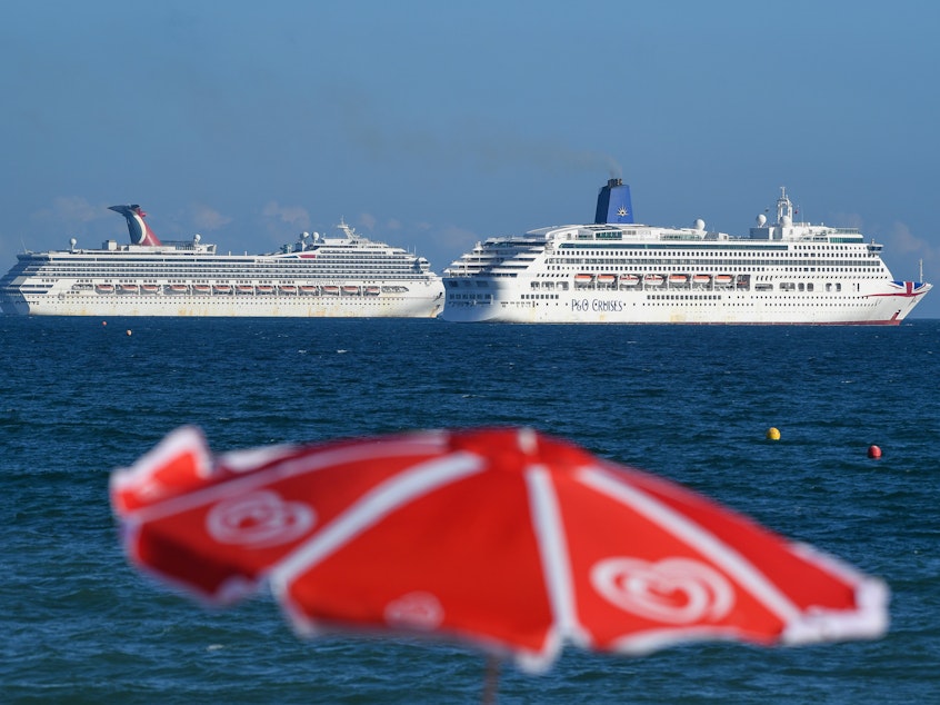 caption: Two Carnival cruise ships seen this summer are anchored in the English Channel as the industry remains hobbled by the coronavirus pandemic.