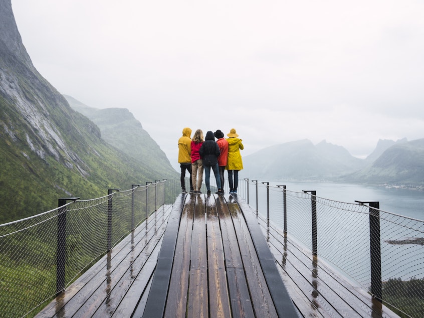 Friends stand on an observation deck on Senja Island, Norway. When traveling as a group, align your expectations ahead of time.