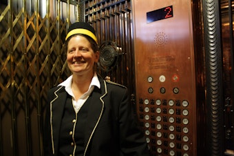 caption: Lesley Holdcroft operates the elevator at Seattle's historic Smith Tower. 