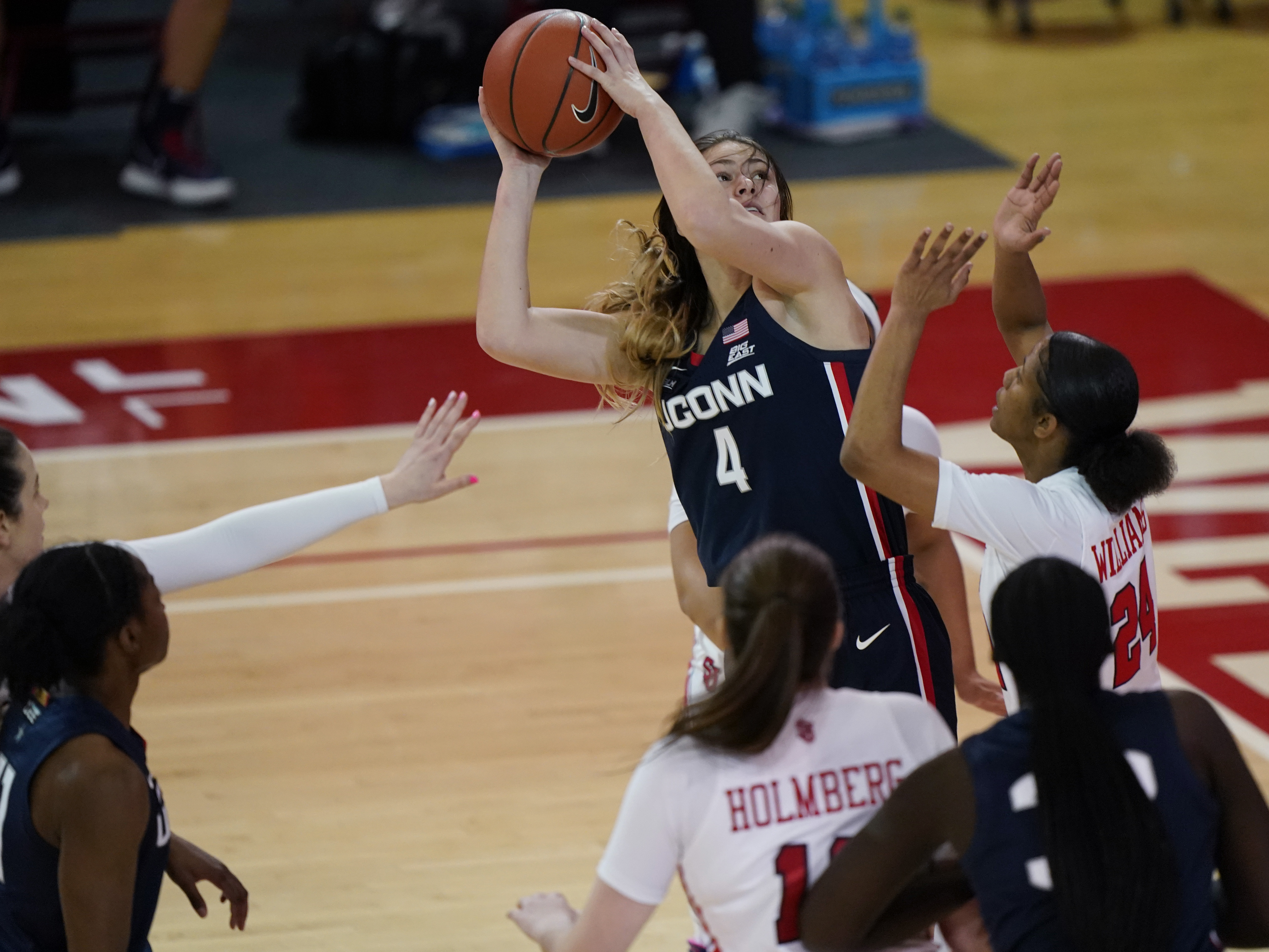 caption: Connecticut guard Saylor Poffenbarger (4) is defended by St. John's guard Danaijah Williams (24) and forward Cecilia Holmberg (11) during the fourth quarter of an NCAA college basketball game in New York last month. The women's NCAA championship begins Sunday.