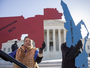 caption: Demonstrators opposed to partisan gerrymandering hold up representations of congressional districts from North Carolina (left) and Maryland (right) outside the U.S. Supreme Court in Washington, D.C., in 2019.