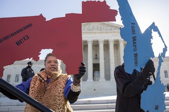caption: Demonstrators opposed to partisan gerrymandering hold up representations of congressional districts from North Carolina (left) and Maryland (right) outside the U.S. Supreme Court in Washington, D.C., in 2019.