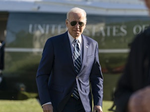 caption: President Biden walks to speak with reporters as he returns to the White House Friday.