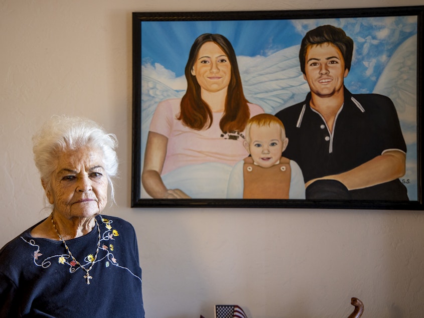 caption: Donna Casasanta poses in front of a painting showing her late son, Harold Dean Clouse Jr., with Clouse's wife, Tina Gail Linn, and their daughter, Holly Marie Clouse, at Casasanta's Edgewater, Fla., home on Friday, Jan. 14, 2022.