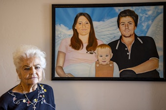 caption: Donna Casasanta poses in front of a painting showing her late son, Harold Dean Clouse Jr., with Clouse's wife, Tina Gail Linn, and their daughter, Holly Marie Clouse, at Casasanta's Edgewater, Fla., home on Friday, Jan. 14, 2022.