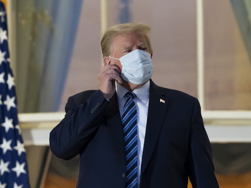 caption: President Trump removes his mask upon returning to the White House on Monday after undergoing treatment for COVID-19 at Walter Reed National Military Medical Center in Bethesda, Md.