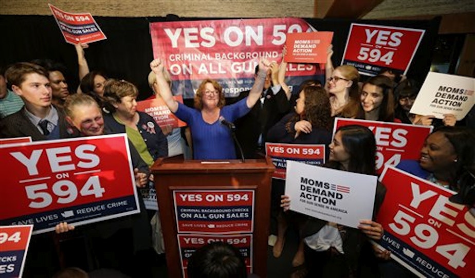caption: Cheryl Stumbo, center, raises her arms as she finishes speaking at an election night party for Initiative 594, a measure seeking universal background checks on gun sales and transfers, Tuesday, Nov. 4, 2014, in Seattle. 