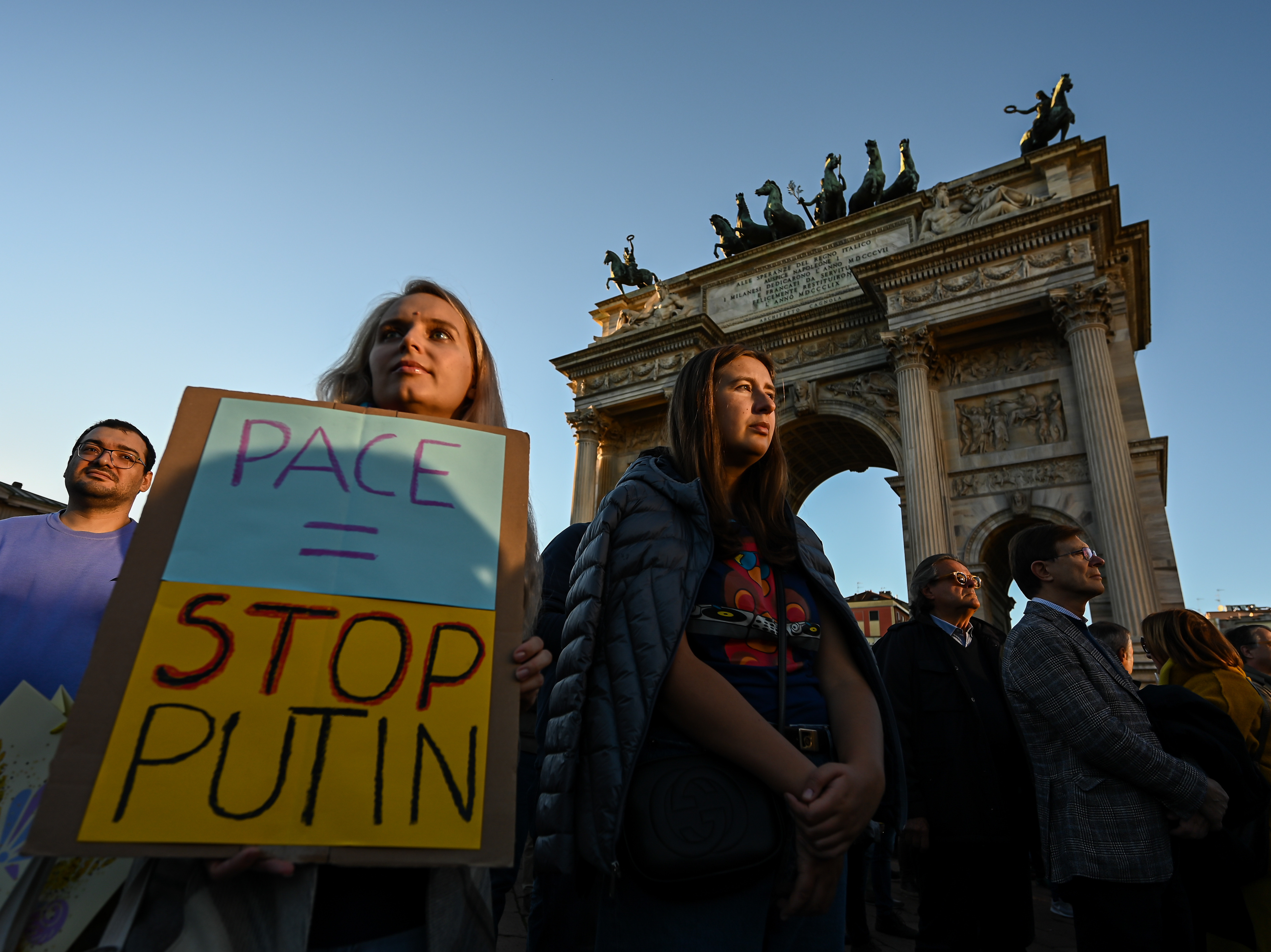 caption: A woman holds a placard reading "Peace = Stop Putin" during a rally in support of Ukraine at Arco della Pace in Milan, Italy on Saturday.
