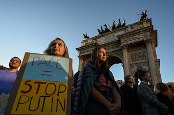 caption: A woman holds a placard reading "Peace = Stop Putin" during a rally in support of Ukraine at Arco della Pace in Milan, Italy on Saturday.
