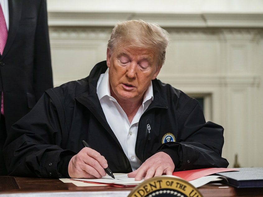 caption: President Trump signs an $8.3 billion emergency spending bill in the White House Friday. That's significantly more than he originally requested from Congress.