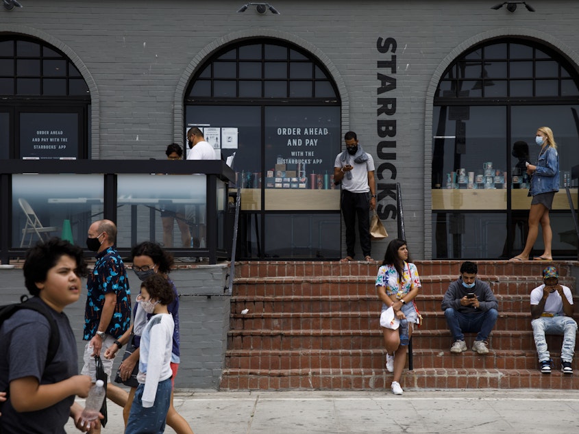 caption: People gathered outside of a Starbucks coffee shop at Venice Beach in Los Angeles last month. The company's order for all customers to wear masks will take effect on July 15.