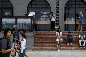caption: People gathered outside of a Starbucks coffee shop at Venice Beach in Los Angeles last month. The company's order for all customers to wear masks will take effect on July 15.