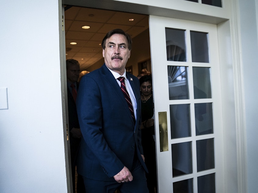 caption: MyPillow CEO Mike Lindell walks out ahead of then-President Donald Trump at the White House in March 2020.