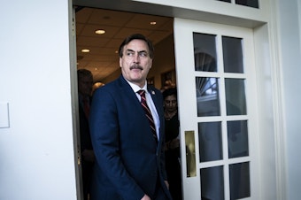 caption: MyPillow CEO Mike Lindell walks out ahead of then-President Donald Trump at the White House in March 2020.