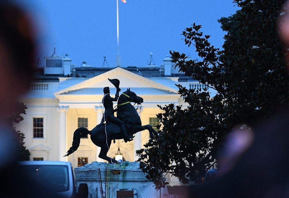 caption: Police officers stand guard with the statue of former President Andrew Jackson after protesters tried to topple it Monday in Lafayette Square in Washington, D.C.
