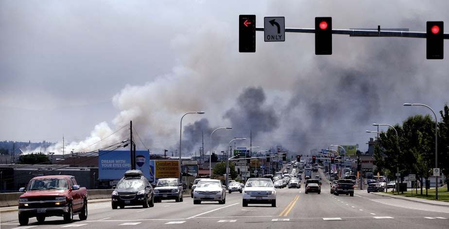 caption: Smoke from several warehouses on fire, thought to have been sparked by embers from a wildfire that hit homes on a nearby hillside, fills the sky Monday, June 29, 2015, in Wenatchee, Wash.