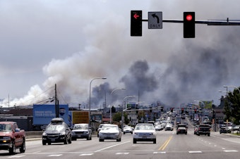 caption: Smoke from several warehouses on fire, thought to have been sparked by embers from a wildfire that hit homes on a nearby hillside, fills the sky Monday, June 29, 2015, in Wenatchee, Wash.