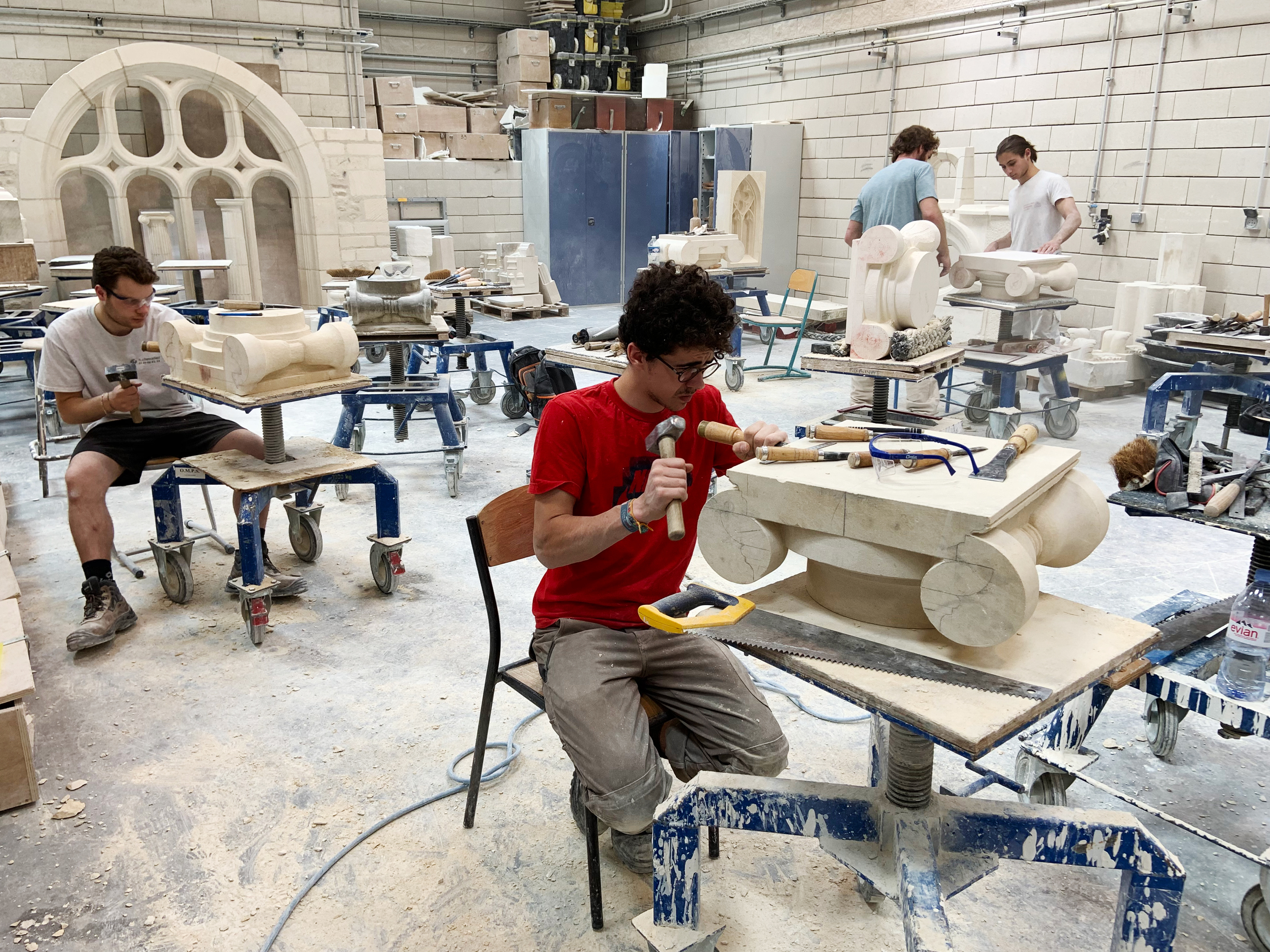 caption: Students chip and chisel away at heavy slabs of stone in the workshops of the Hector Guimard high school, less than three miles from Paris' Notre Dame cathedral.